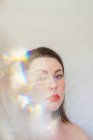 Portrait of a beautiful woman with multi coloured light across her face — Stock Photo