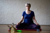Portrait of a senior woman sitting cross-legged meditating — Stock Photo