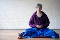 Портрет пожилой женщины, сидящей со скрещенными ногами — стоковое фото