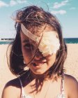 Портрет усміхненої дівчини на пляжі з квітковою пов'язкою, що прикриває її око, шпиль. — стокове фото