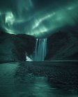 Luci settentrionali sulla cascata di Skogafoss, Islanda — Foto stock