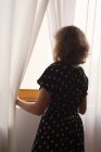 Teenage girl looking through a window — Stock Photo