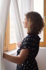Adolescente olhando através de uma janela — Fotografia de Stock