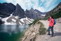 Woman looking through binoculars on a trail between Lake Louise and Lake Agnes, Banff National Park, Alberta, Canadá — Fotografia de Stock