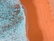 Luftaufnahme von Sandküste und welligem Meer bei sonnigem Tag — Stockfoto