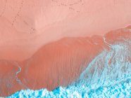 Воздушный вид на песчаное побережье около волнистого моря в солнечный день — стоковое фото