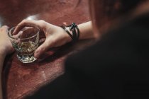Una mujer bebiendo whisky en un bar - foto de stock