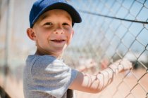 Porträt eines lächelnden Jungen, der neben einem Baseballfeld steht, Laguna Beach, Kalifornien, Vereinigte Staaten — Stockfoto