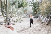 Мать фотографирует свою дочь, бегущую в пустыне, Палм-Спрингс, Калифорния, США — стоковое фото