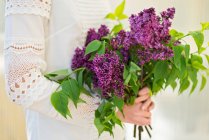Adolescente tenant un bouquet de fleurs lilas à un mariage — Photo de stock