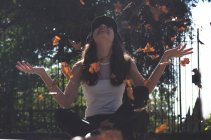 Девочка-подросток, сидящая на земле, бросает листья в воздух, Аргентина — стоковое фото