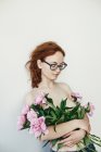 Porträt einer jungen Frau mit Brille und Pfingstrosen — Stockfoto