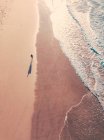 Vista aérea del hombre con surf caminando a lo largo de la playa 13, Victoria, Australia - foto de stock