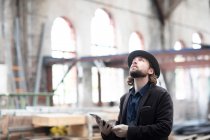 Портрет человека, стоящего в отреставрированном здании и смотрящего на цифровой планшет — стоковое фото