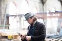 Retrato de um homem em pé num edifício a ser renovado a olhar para um tablet digital — Fotografia de Stock