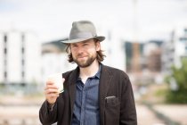 Портрет усміхненого чоловіка, що стоїть на відкритому повітрі з гарячим напоєм — стокове фото