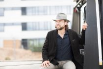 Portrait of a smiling man sitting on the back of a truck — Stock Photo