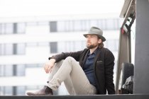 Portrait of a man sitting on the back of a truck with his arm outstretched — Stock Photo