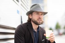 Portrait d'un homme assis à l'extérieur tenant une tasse de café — Photo de stock