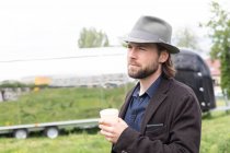 Портрет чоловіка, що стоїть на відкритому повітрі, тримає чашку кави — стокове фото