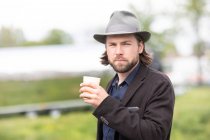 Портрет человека, стоящего на улице и держащего чашку кофе — стоковое фото