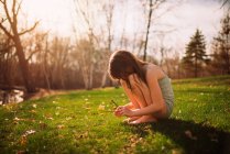 Menina sentada na grama olhando para galhos, Estados Unidos — Fotografia de Stock