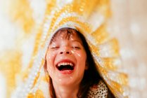 Смеющаяся девушка с веснушками, покрытыми тканью и солнечными лучами на лице — стоковое фото