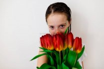 Süßes kleines Mädchen posiert mit roten Tulpen — Stockfoto