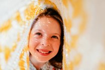 Laughing girl with freckles covered with fabric and sunbeams on face — Stock Photo