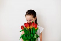 Мила маленька дівчинка позує з червоними тюльпанами — стокове фото