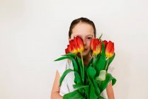 Мила маленька дівчинка позує з червоними тюльпанами — стокове фото