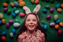 Porträt eines jungen Mädchens mit Hasenohren, umgeben von Ostereiern — Stockfoto