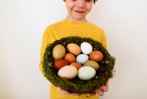Portrait of a smiling boy holding a nest with fresh eggs — Stock Photo