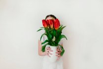 Portrait of girl holding vase of tulips — Stock Photo