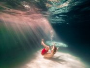 Niño acurrucado en el fondo de una piscina - foto de stock