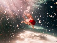 Мальчик плавает под водой в бассейне — стоковое фото