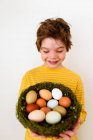 Retrato de un niño sosteniendo un nido con huevos frescos - foto de stock