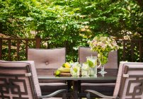 Limonade in Krug und Tassen auf dem Tisch im Garten. — Stockfoto