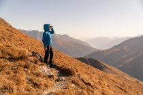 Турист, стоящий в горах и смотрящий в бинокль, Бад Мбаппе, Австрия — стоковое фото