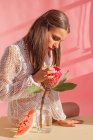 Frau sitzt auf einem Tisch und berührt eine Protea-Blume — Stockfoto