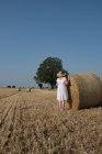 Женщина, стоящая у тюка сена в поле, Франция — стоковое фото