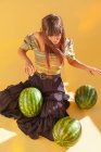 Lächelnde Frau sitzt auf dem Boden und benutzt Wassermelonen als musikalische Trommeln — Stockfoto