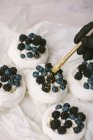 Woman decorating Pavlova desserts with blueberries and blackberries — Stock Photo