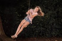 Garota sorridente em um balanço de corda no jardim, Dinamarca — Fotografia de Stock