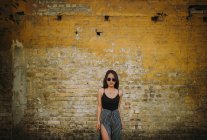 Stylish asian young woman standing in front of old brick wall — Stock Photo