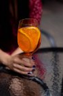 Woman sitting at a table holding an aperol spritz cocktail — Stock Photo