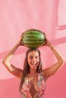 Smiling woman holding a watermelon above her head — Stock Photo