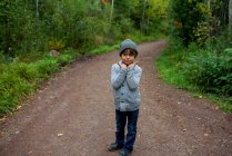 Portrait d'un garçon debout dans la forêt avec des champignons sur les doigts, États-Unis — Photo de stock