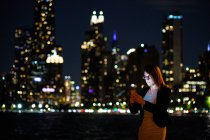 Frau benutzt ihr Mobiltelefon mit der Skyline der Stadt im Hintergrund, Chicago, Illinois, USA — Stockfoto
