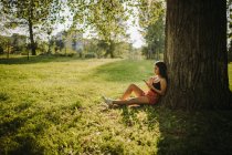Frau sitzt unter einem Baum und blickt auf ihr Handy, Serbien — Stockfoto